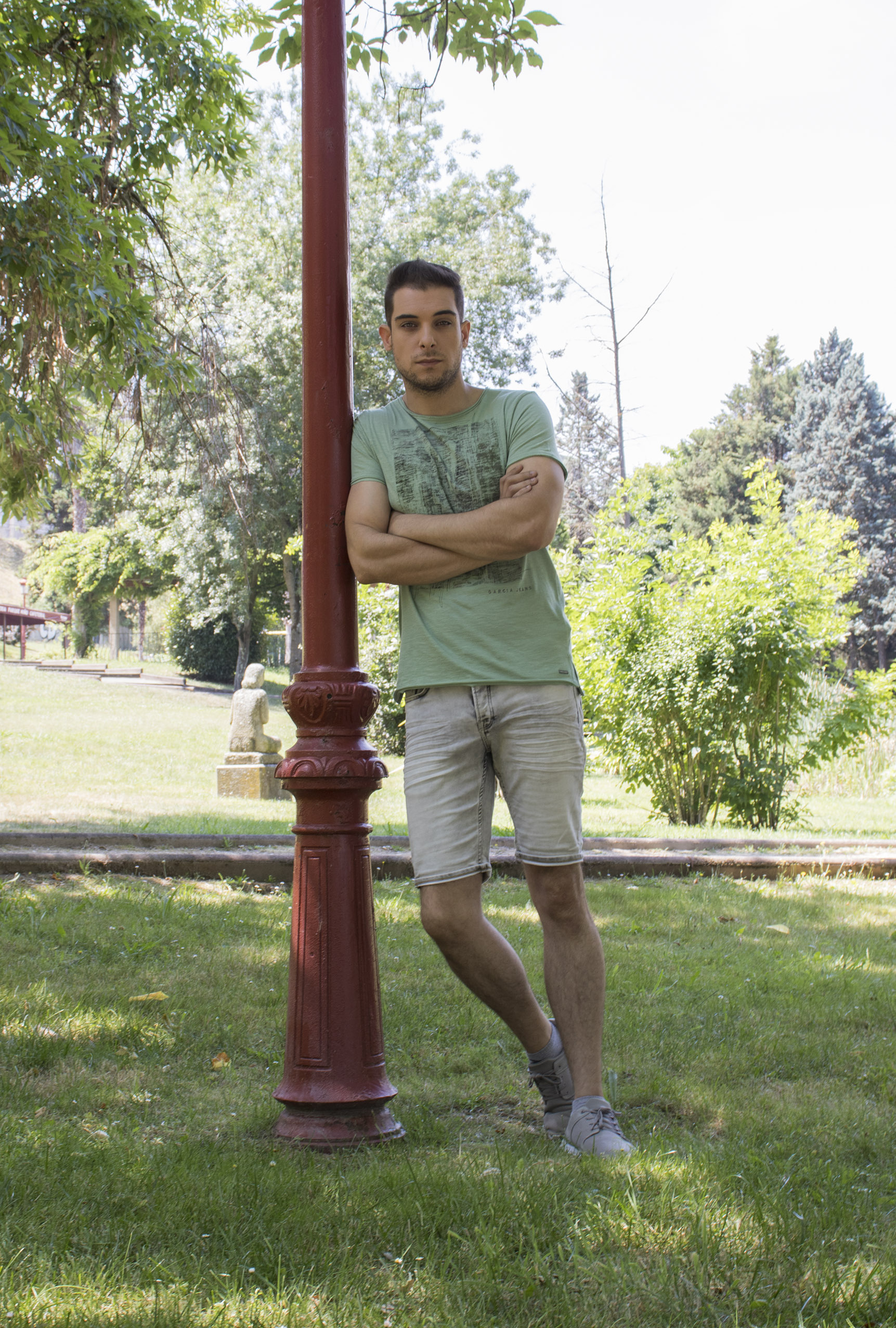 Outfit hombre: look de camiseta verde con dibujo en negro y pantalones cortos en gris lavado